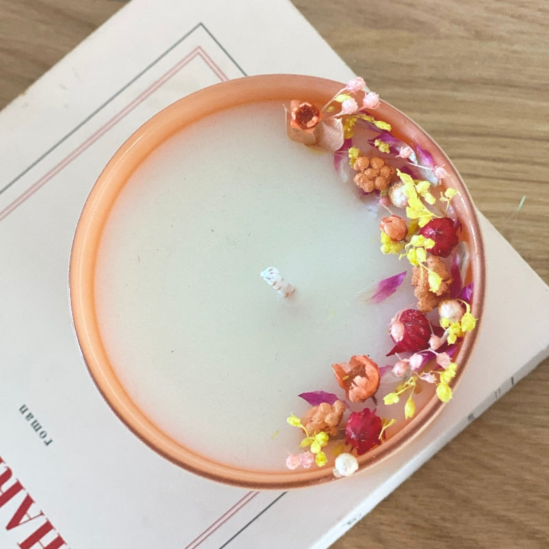 bougie fleurie decoree de fleurs rose jaune et pêche dans un pot en verre couleur pêche