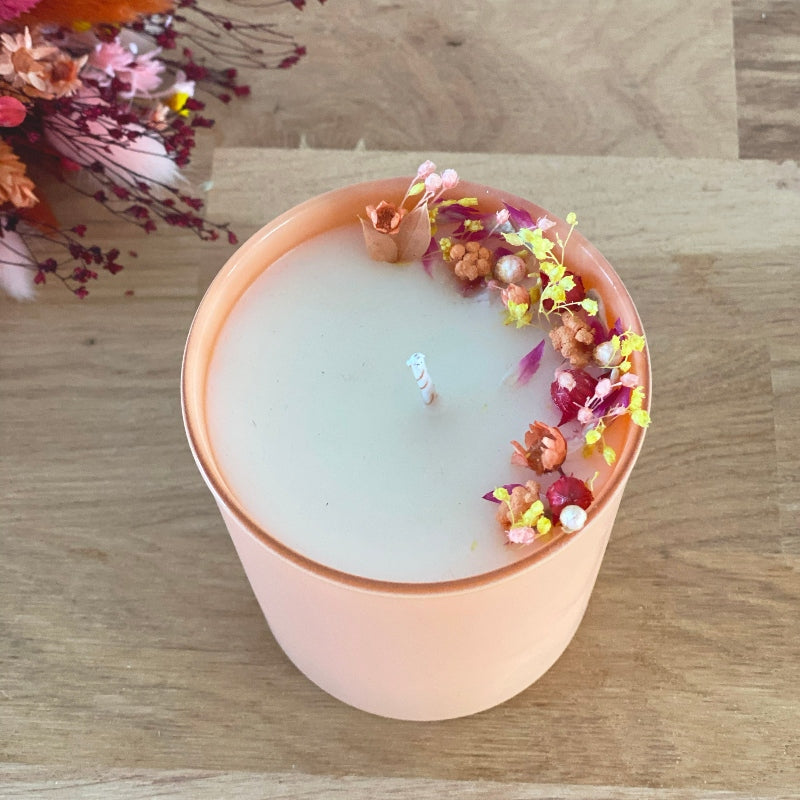 bougie fleurie decoree de fleurs rose jaune et pêche dans un pot en verre couleur pêche