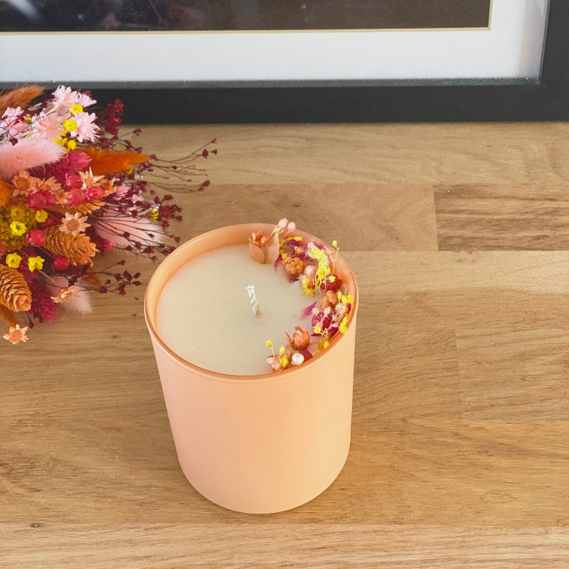 bougie fleurie decoree de fleurs rose jaune et pêche dans un pot en verre couleur pêche