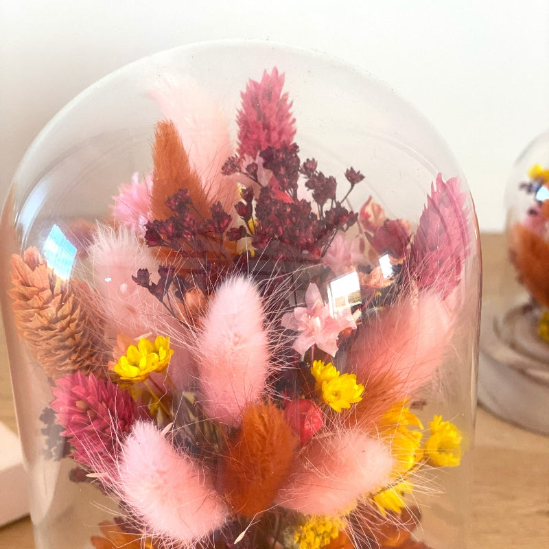composition florale fleurs sechees roses jaunes et ocres sous un globe en verre