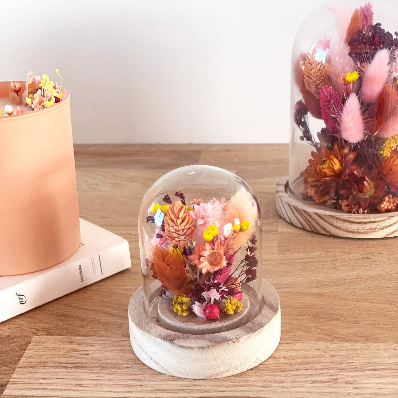 composition florale fleurs sechees roses jaunes et ocres sous un globe en verre