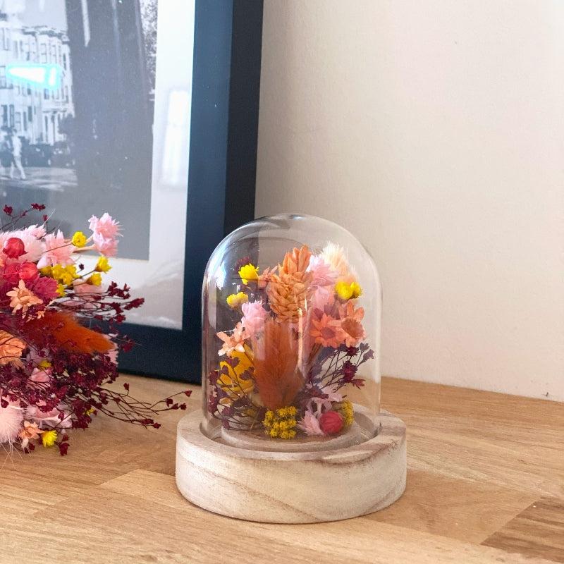 composition florale fleurs sechees roses jaunes et ocres sous un globe en verre