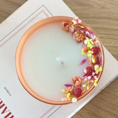 bougie fleurie decoree de fleurs rose jaune et pêche dans un pot en verre couleur pêche
