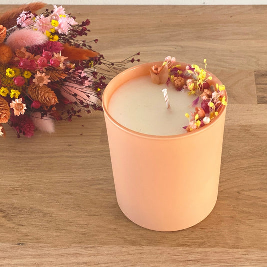 bougie fleurie decoree de fleurs rose jaune et pêche dans un pot en verre couleur pêche