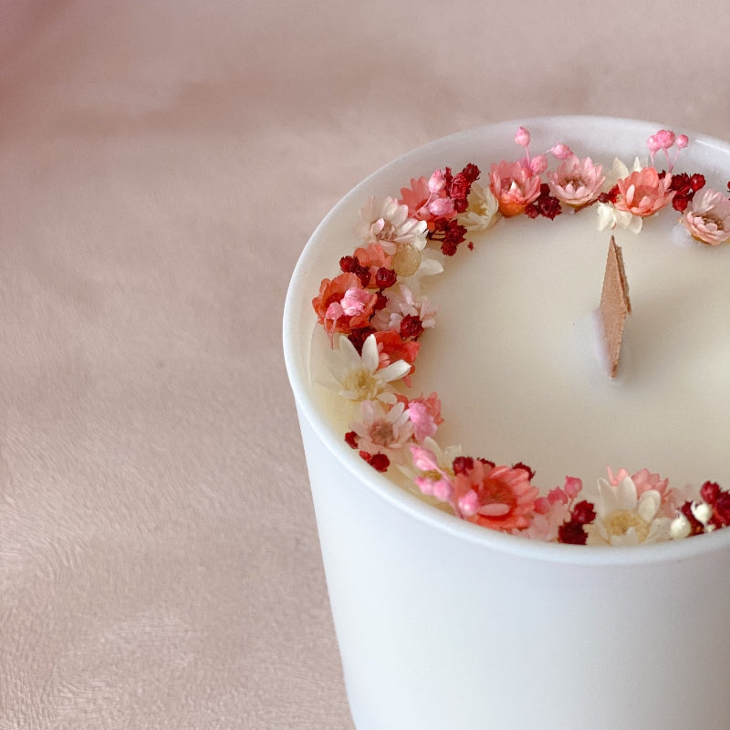 bougie en cire naturelle, décorée de petites fleurs sechees roses et blanches dans un pot blanc mat avec meche en bois. 