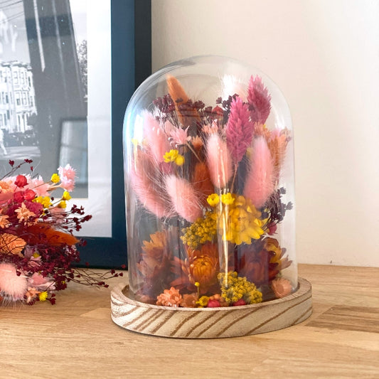 composition florale fleurs sechees roses jaunes et ocres sous un globe en verre