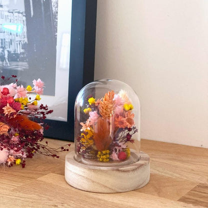 composition florale fleurs sechees roses jaunes et ocres sous un globe en verre