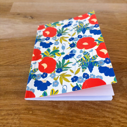 carnet de notes format A6 motif floral maximaliste comme un champ de fleurs très coloré dans les tons rouge, bleu, vert et blanc. 