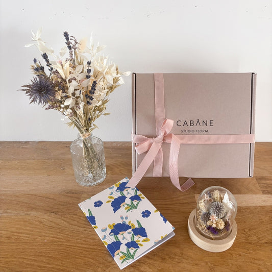 coffret cadeau basile composé d'un bouquet de fleurs séchées blanc et bleu, un petit vase assorti et un mini globe fleuri