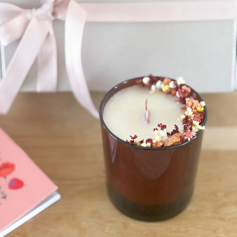 bougie fleurie capucine dans un pot ambré, avec meche en bois, décorée de petites fleurs dans les tons rose, jaune, orange, blanc et rouge