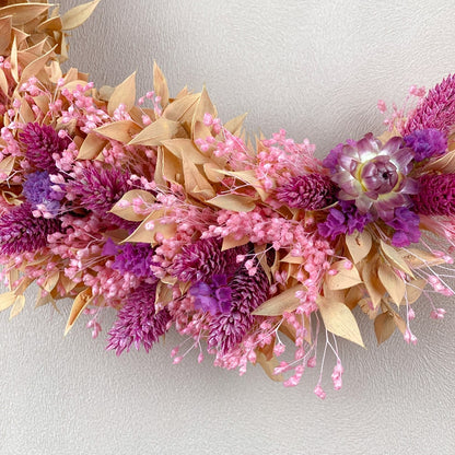 couronne de fleurs sechees avec ruscus peche, broom broom rose, statice violet et immortelles roses