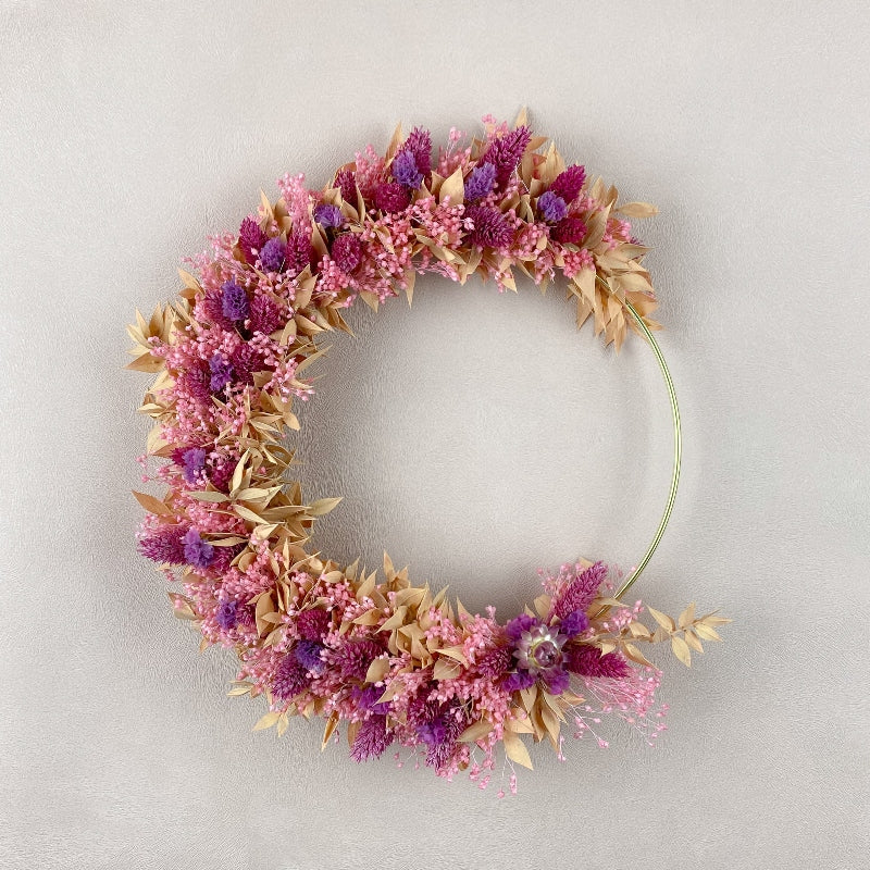 couronne de fleurs sechees louise à accrocher au mur, couleurs rose violet peche