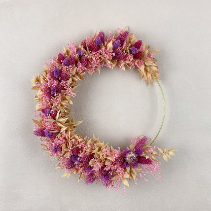 couronne de fleurs sechees louise à accrocher au mur, couleurs rose violet peche