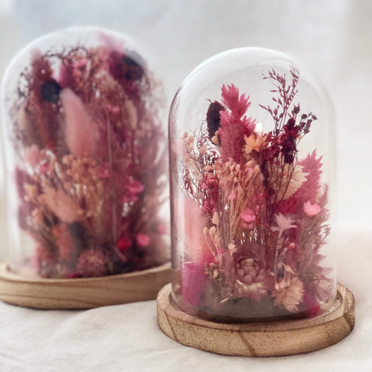 composition fleurs sechees dans les tons roses socle en bois et globe en verre